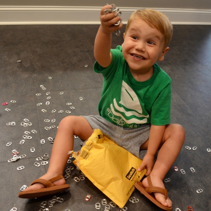 Child with displaying aluminum can pull tabs