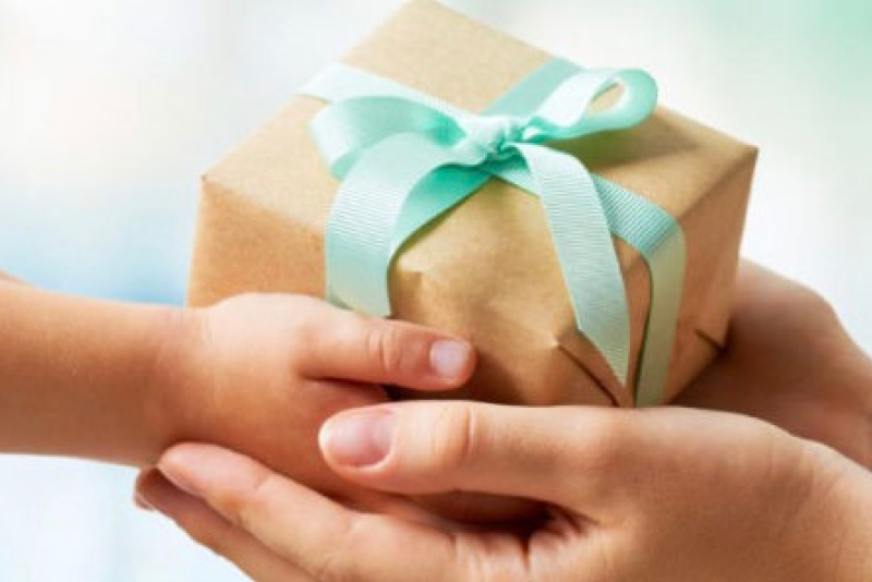 Adult hands + child hands holding packaged gift