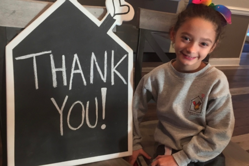 Child sitting next to thank you sign